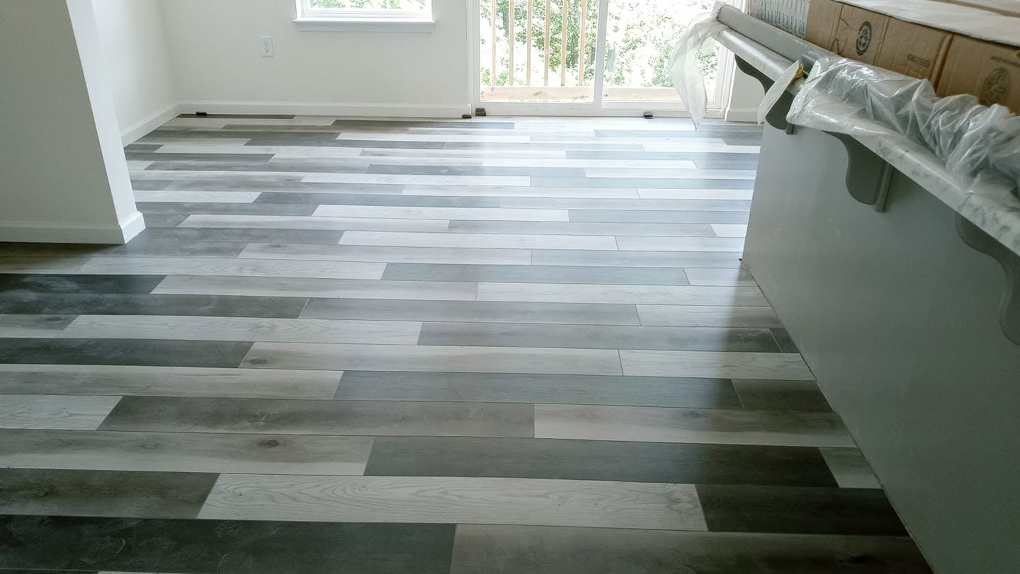 Clark’s gray wood-look flooring flowing through a bright kitchen and dining space